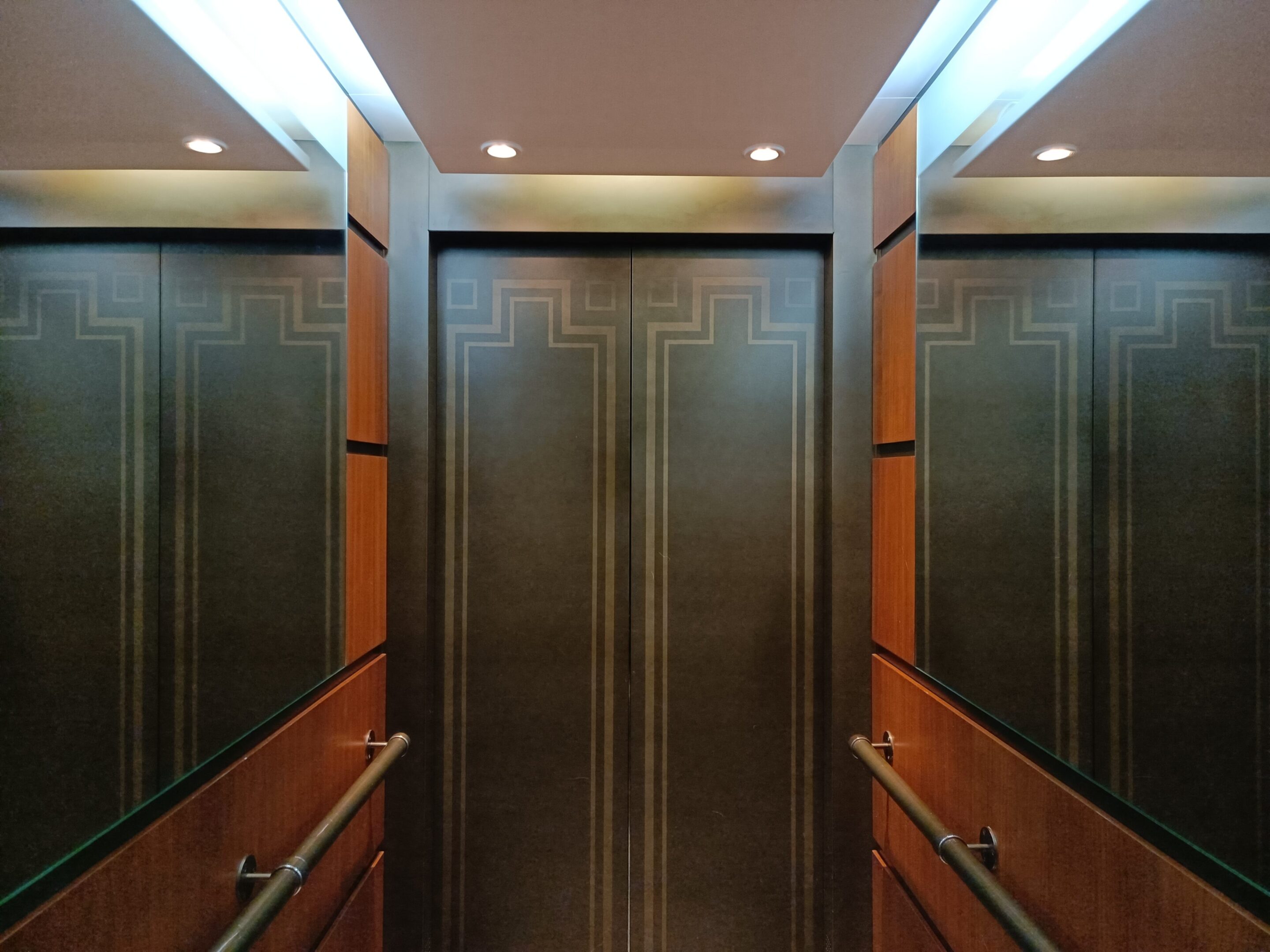 Custom fabricated elevator interior with fluted bronze panels and backlit glass